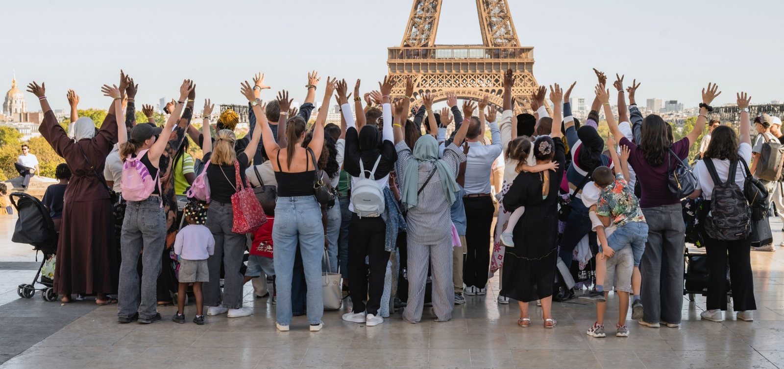 Les familles de la Maison Pauline Kergomard et les collaborateurs de Goron, bras levés face à la tour Eiffel au Trocadéro